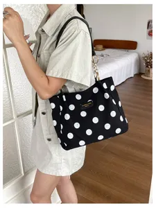 Detailed macro view of a black and white polka dot canvas tote bag with chain straps