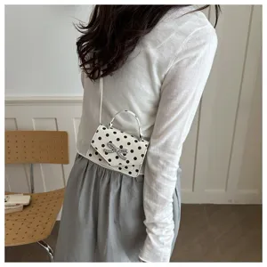 Détail d'un mini sac à main blanc à pois élégant avec un nœud en strass brillant décoratif