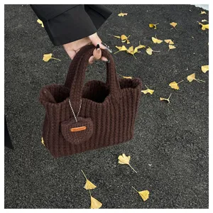 Gros plan d'un sac à main en tricot marron avec étiquette 'Hand Made' sur asphalte