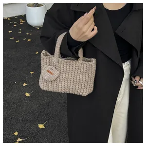 Gros plan d'un sac cabas en tricot beige fait main tenu par un mannequin élégant