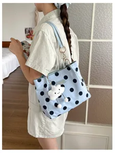 Detail view of a light blue polka dot tote bag featuring a cute white cloud keychain charm