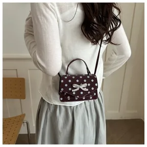 Vue détaillée d'un mannequin portant un sac à pois bordeaux avec un nœud en strass