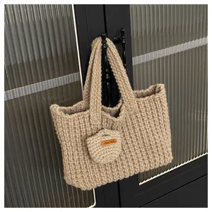 Gros plan d'un sac cabas en laine tricoté main kaki suspendu à une poignée de porte.