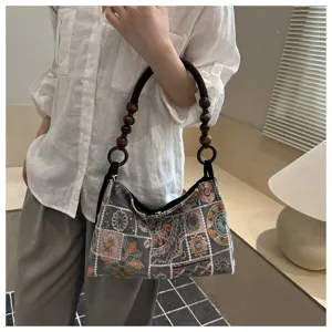 Borsa tote ricamata in stile cinese con manico in perle di legno portata da una modella