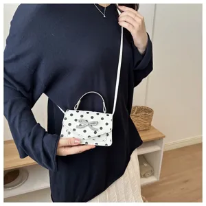 Gros plan d'un mini sac carré à pois avec un nœud en strass étincelant élégant