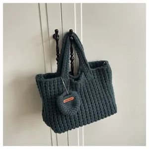 Détail d'un sac cabas tricoté main gris foncé avec étiquette en cuir 'Hand Made'