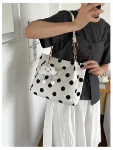Close-up of white polka dot tote bag with gold chain straps and a cute cloud charm