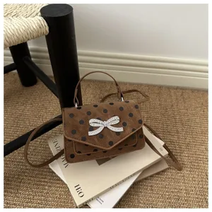 Vue rapprochée de la texture à pois marron et du nœud en strass du sac à bandoulière