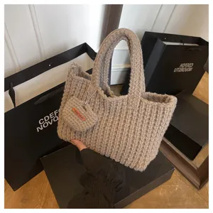 Détail d'un sac à main beige en laine tricoté à la main avec une étiquette rustique 'Hand Made'