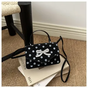 Chic sac à main noir à pois avec un nœud en strass étincelant sur des magazines