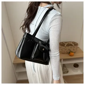 Lifestyle view of vintage black glossy faux leather shoulder bag on a woman