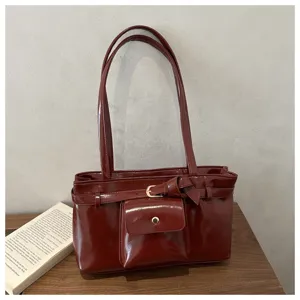 Macro view of vintage burgundy soft leather tote bag featuring a front buckle pocket detail