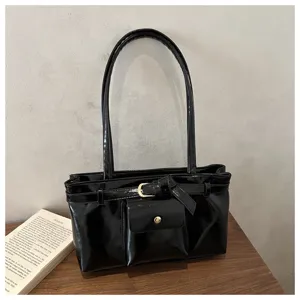 Close-up detail of a vintage black soft leather tote bag featuring a decorative belt buckle