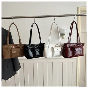 Display of stylish glossy shoulder bags in four colors hanging on a metal garment rack.