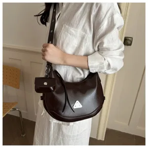Close-up of a dark brown glossy crescent bag with a small hanging coin purse
