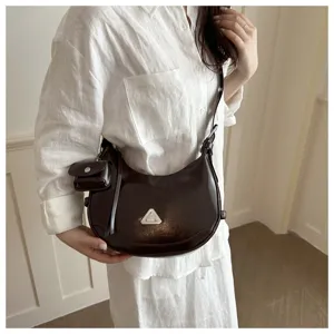 Dark brown crescent hobo bag with silver triangle buckle worn by a model on white shirt
