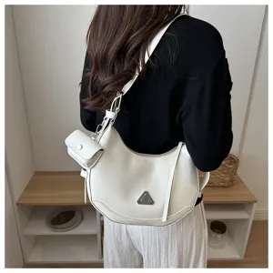 Close-up of a white minimalist crescent hobo bag worn by a model in a stylish interior