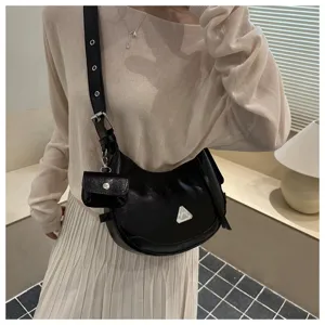 Close-up view of a stylish black leather crescent hobo bag featuring a metal triangle logo