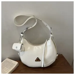 Close-up detail of a white crescent moon hobo bag with a matching small pouch charm