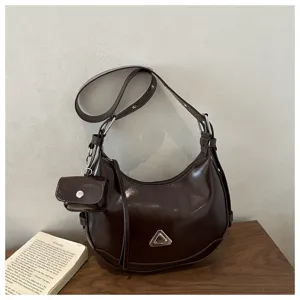 Minimalist dark brown crescent shoulder bag featuring a matching mini pouch.