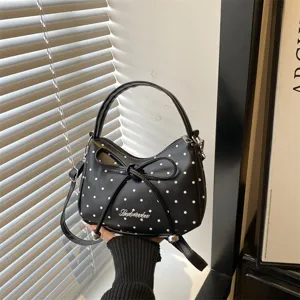 Elegante zwarte handtas met witte polkadots, strikdetail en verstelbare schouderriem