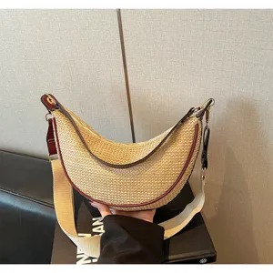 Détail d'un sac demi-lune en paille tressée avec bordure rouge et large bandoulière