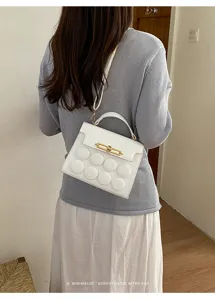 Back view of minimalist white leather crossbody bag with circular embossed design