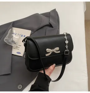 Detaillierte Makroansicht einer schwarzen Unterarmtasche mit eleganter Strass-Schleife