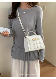 Close-up of a stylish white minimalist handbag featuring unique circular button textures.