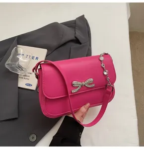 Nahaufnahme der fuchsiafarbenen Damentasche mit glitzernder Strassschleife und Kette