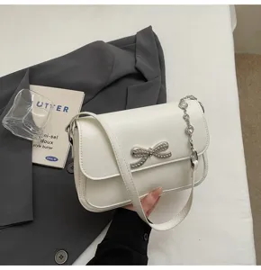 Detailansicht einer schicken weißen Achseltasche mit einer funkelnden Strassschleife