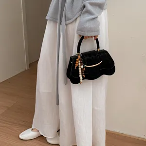 Élégant sac à main noir à imprimé léopard avec une breloque unique en perles de bois.