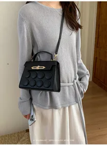 Close-up of a black minimalist retro handbag featuring a unique circular embossed pattern.