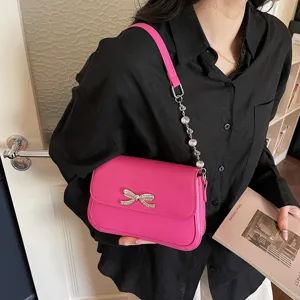 Modische pinkfarbene Unterachseltasche mit funkelnder Kristallschleife und edler Kette.