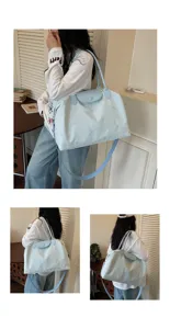 Detailed view of the light blue travel bag showcasing its shoulder strap and embroidery.