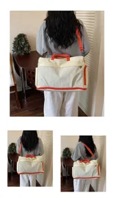 Detailansicht der großen Canvas-Reisetasche mit leuchtend orangen Trägern und praktischen Fächern.
