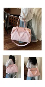 Detailed shot of large pink travel duffel bag with bow embroidery and shoulder strap.