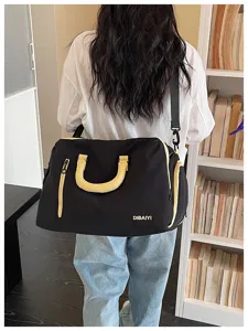Detailaufnahme einer Person von hinten mit einer großen schwarzen Reisetasche mit gelben Griffen.