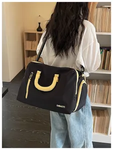 Detailansicht der schwarzen Reisetasche mit gelben Griffen und großem Fassungsvermögen.