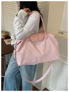 Pink travel bag detail view showing bow embroidery, flap closure, and comfortable shoulder strap.