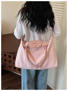 Pink nylon shoulder bag detail, cute bow embroidery and flap design for women travel.