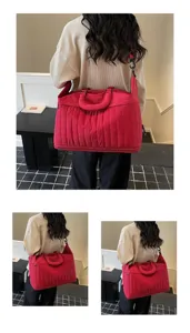 Vue détaillée du sac de voyage rouge matelassé porté par un mannequin en intérieur.