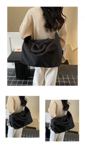 Detail view of the black travel duffel bag, showing large capacity and comfortable strap.