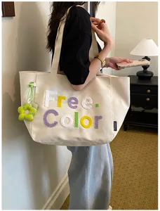 Detailed view of casual canvas tote bag with embroidered letters and cute flower pendant charm.