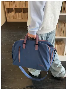 Detailansicht der blauen Reisetasche mit Fronttasche und Reißverschluss in Modelhand.