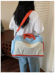 Detaillierte Rückansicht einer großen Reisetasche mit orangefarbenen Griffen und Gurten.
