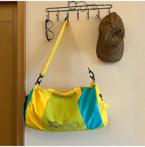 Colorblock travel duffel bag detail, large capacity sports gym bag hanging on wall hook.