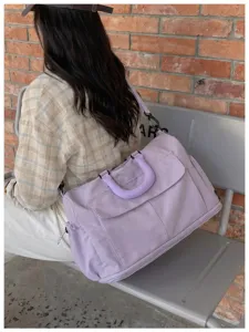 Detail shot of a large capacity travel duffel bag in light purple, ergonomic handle and strap.