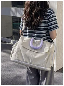 Detailed view of large capacity travel duffel bag worn on shoulder with purple handle cover.