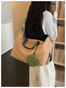 Detailed view of the large capacity travel duffel bag with green straps and coin purse charm.